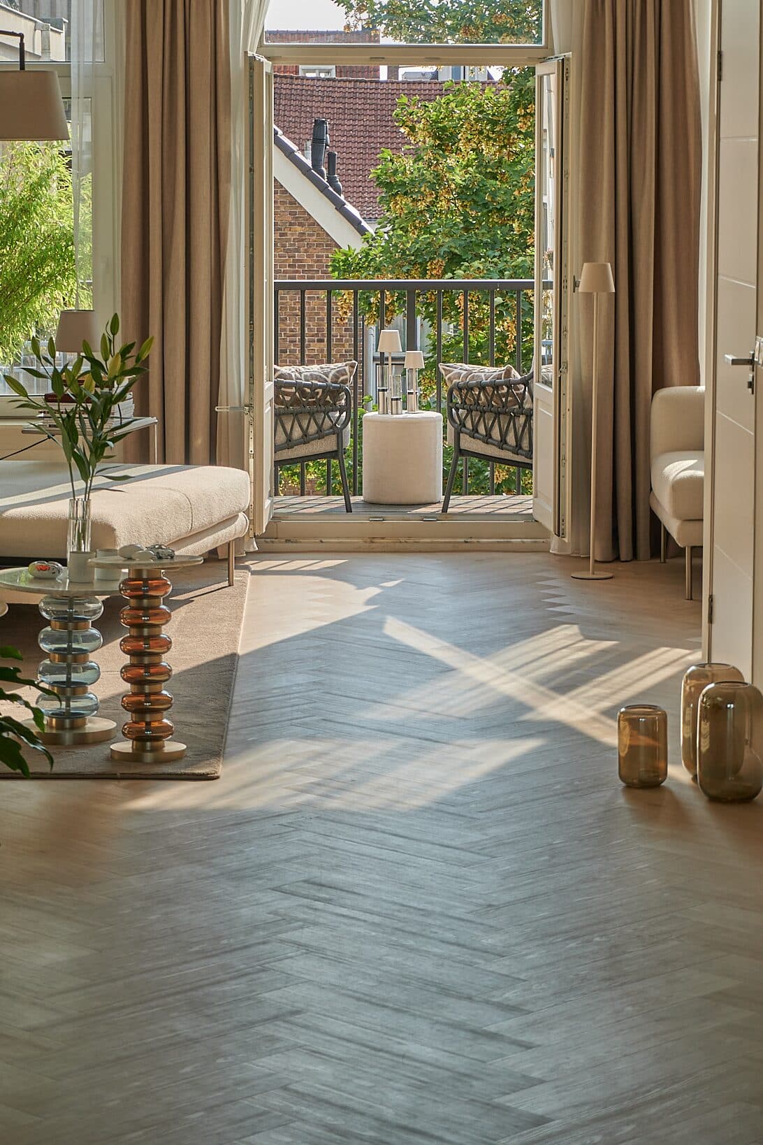 Herringbone oak floor laid by hand, morning light from open balcony doors