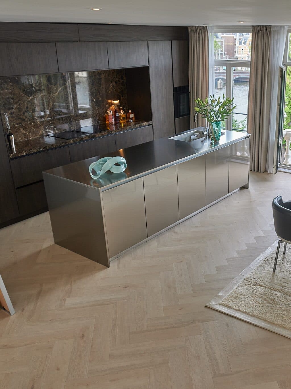 Finished kitchen in dark oak with an Emperador marble splashback and champagne metal island