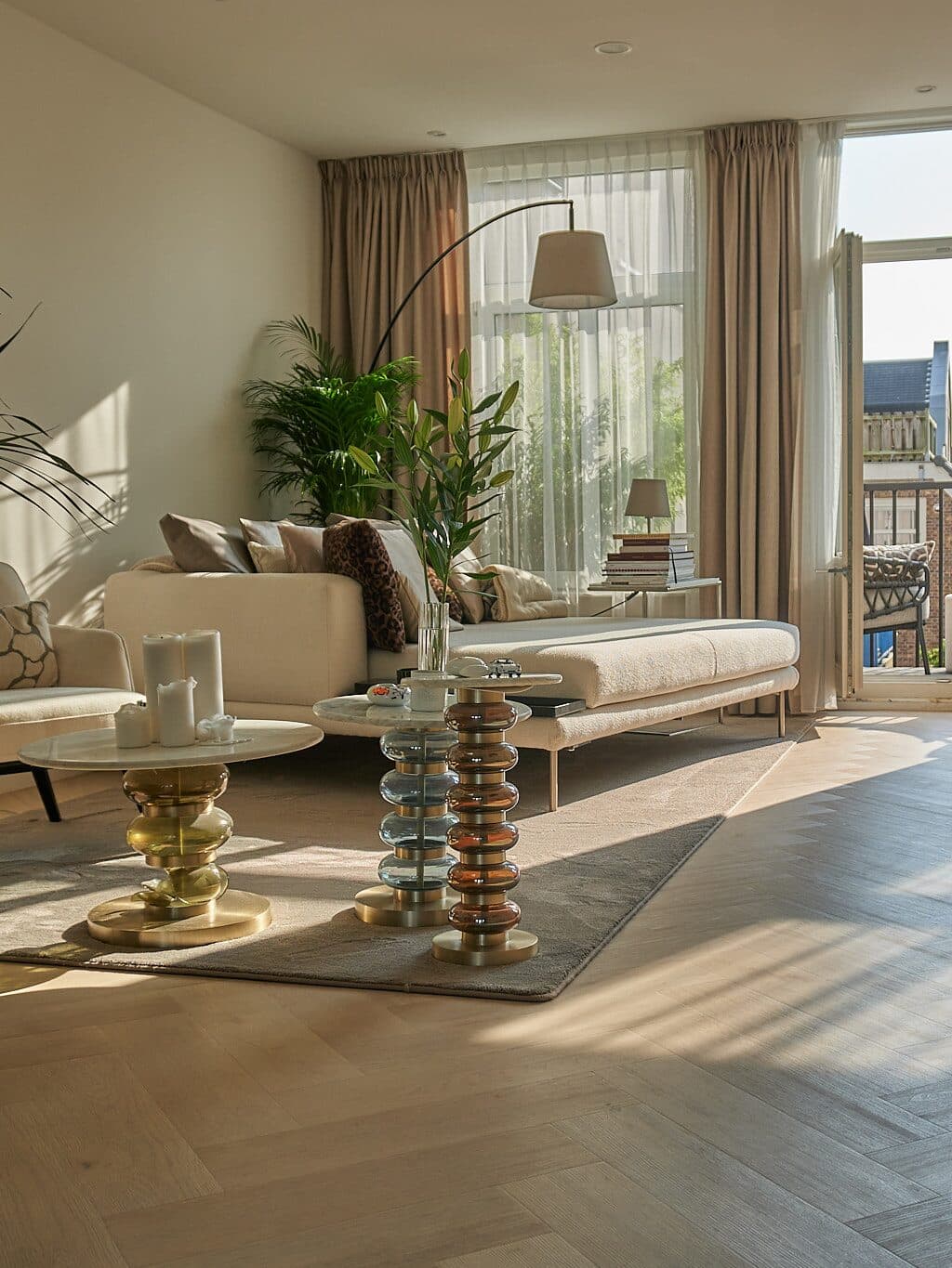 A finished living room handed back, with oak herringbone floor, morning sun and a balcony beyond