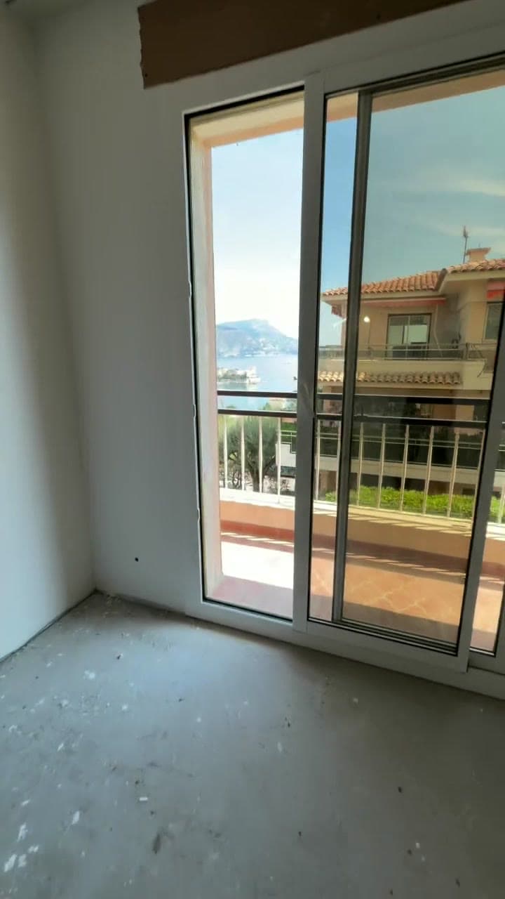 A stripped room with new frames fitted, opening onto a balcony above the sea