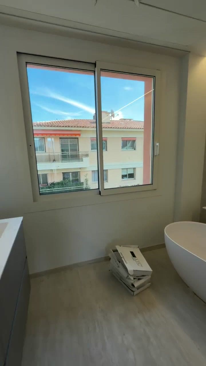 A freestanding bath set beneath a window in a bathroom nearing completion